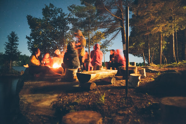 eight to ten undisguishable people sitting around campfire in winter