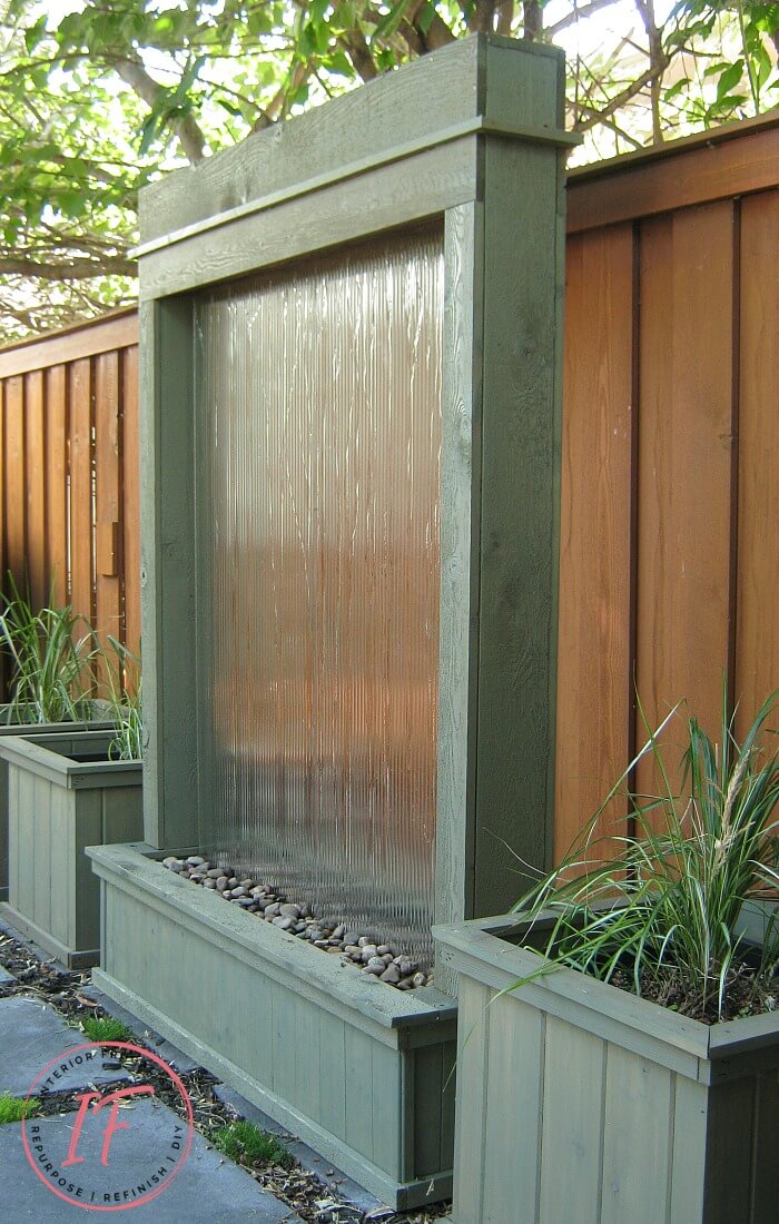 An amazing DIY Outdoor Water Feature for under $300 for a backyard deck or patio using recycled tempered glass. The outdoor fountain is also illuminated at night with solar flood lights. A budget-friendly water feature plus privacy screen for those who know how to rock power tools.