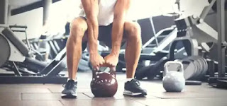 A man honing his dumbbell sumo squat technique.