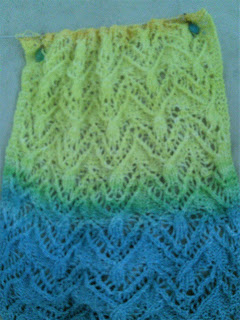 lace knitting on a straight needle.  The lace is knit in a gradient running from blue, through green, to yellow.