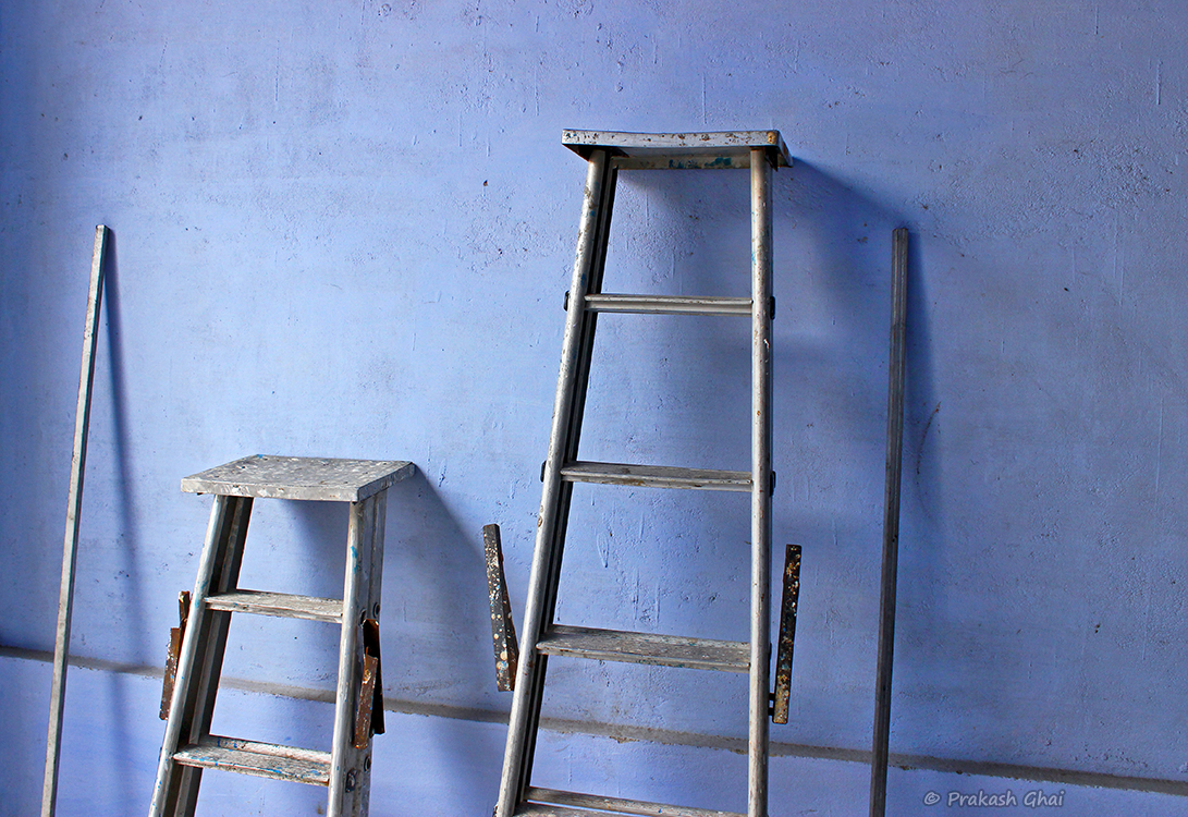 A Minimalist Photo of Metal Ladders at Diggi Palace Jaipur Literature Art Festival, against a blue wall.