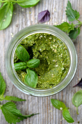 Brennnessel-Basilikum-Pesto ist in einem Glas angerichtet und mit frischem Basilikum und Brennnesseln garniert.