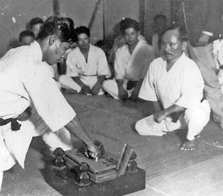 Gichin Funakoshi teaching his student board breaking