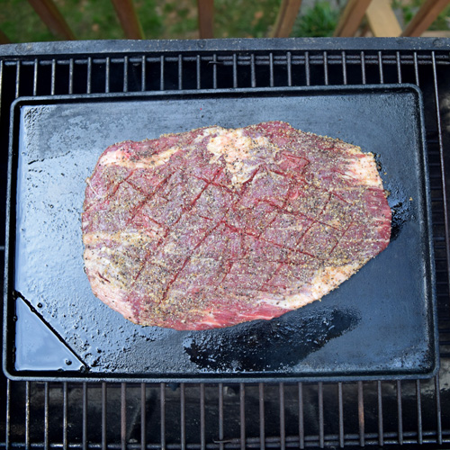 Flank steak on a flat top griddle on the grill