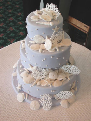 Light blue wedding cake with three round tiers and decorated with lovely sea
