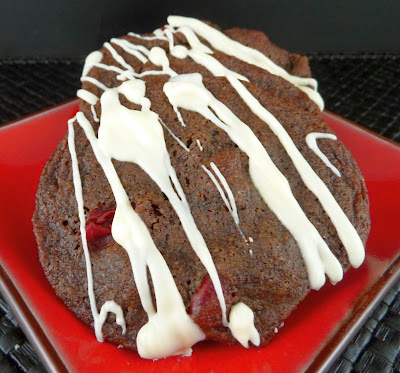 Chocolate cookies with cherries, drizzled with white chocolate, photographed on a square red plate.