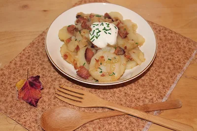 Serving hot German potato salad topped with sour cream.