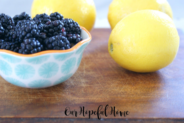 thrift store wooden cutting board with scratches blackberries lemons