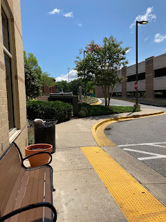 Photo showing sky, trees, bench in front of a building