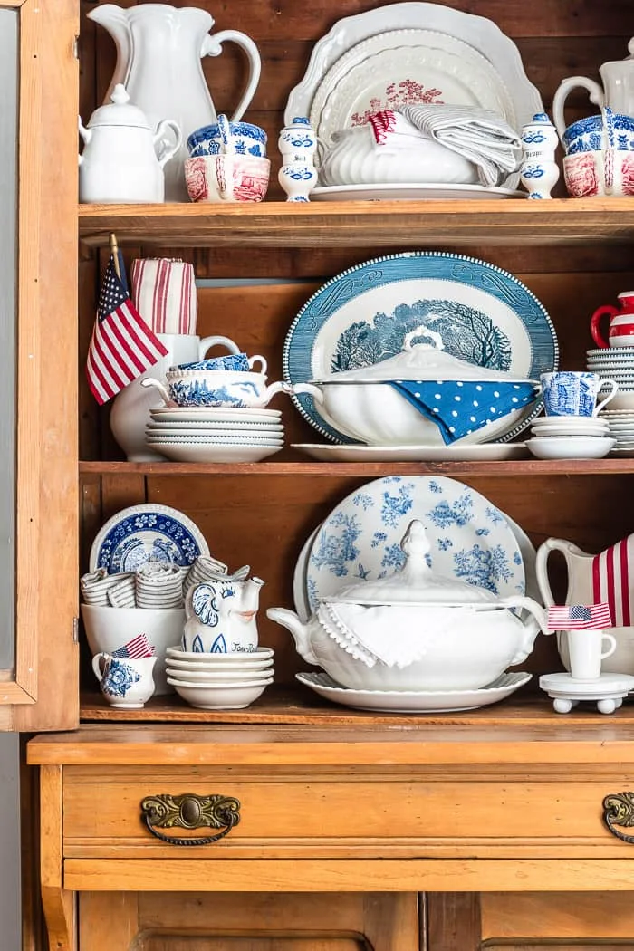 shelves of blue and red transferware, white ironstone and miniature flags