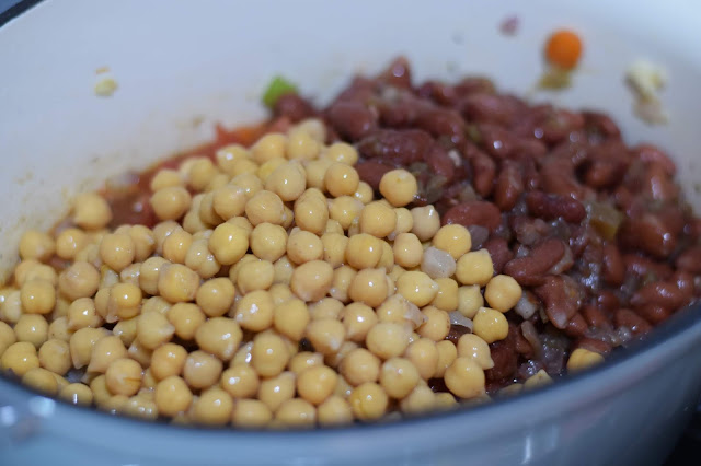 A can of chickpeas and a can of red beans in the pot. 