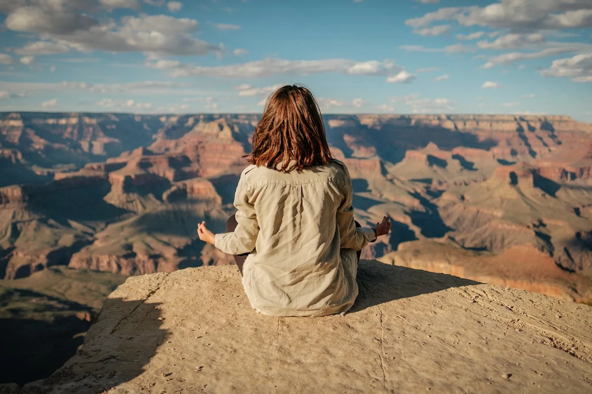 woman meditates on a rock canyon