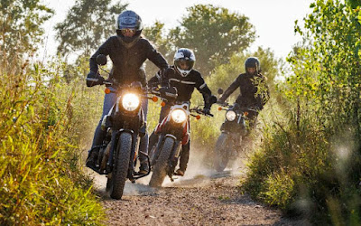 Three Scram 411 motorcycles ride in dirt.