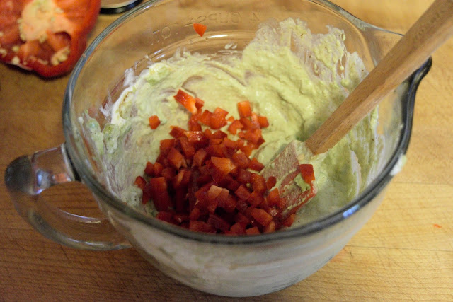 A picture of diced red pepper being added to the dressing in a mixing bowl. 