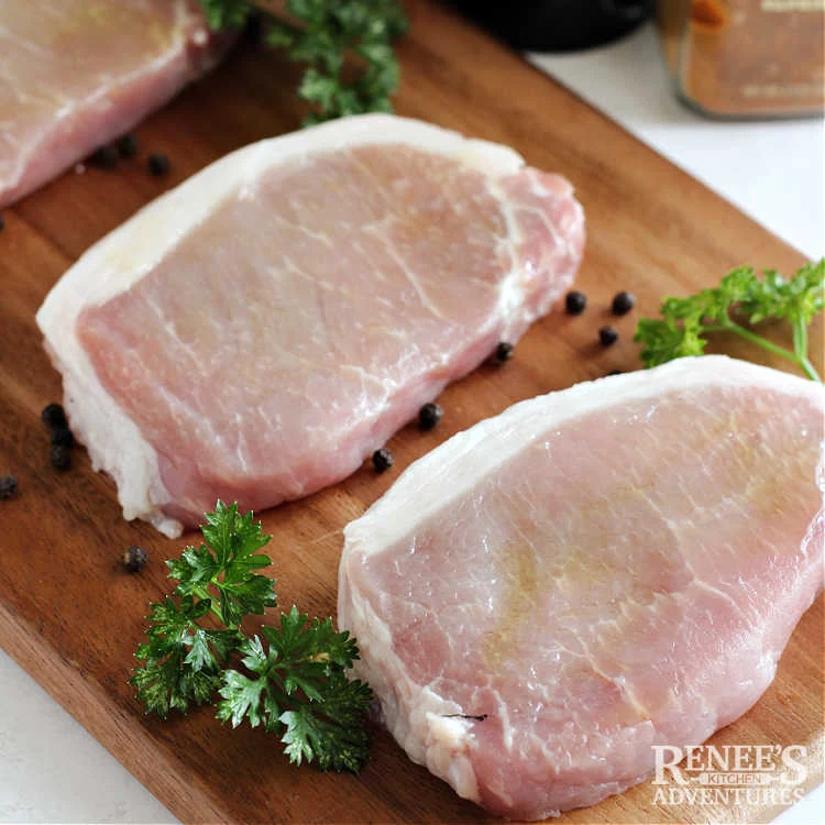 Boneless pork chops on board brushed with olive oil ready for seasoning and to be cooked in air fryer