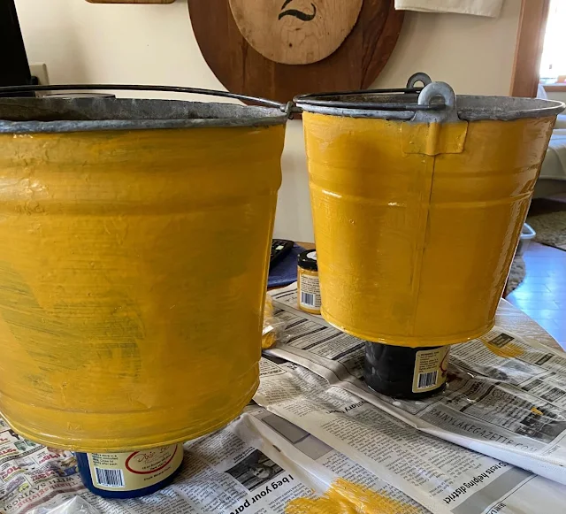 Photo of two galvanized buckets being painted with Colonel Mustard.