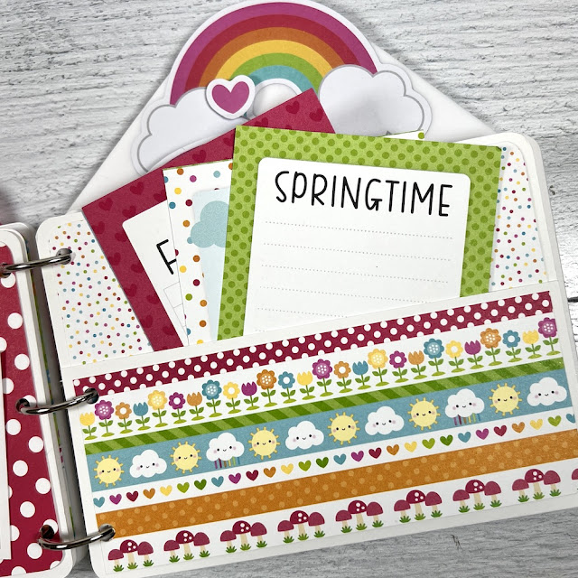 Spring Scrapbook Album Page with flowers, rainbows, clouds, mushrooms, and a pocket with journaling cards