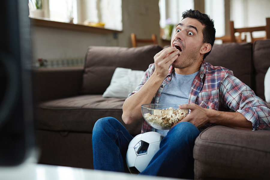 pemuda makan sambil nonton tv