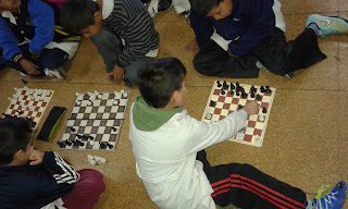 Alumnos jugando ajedrez en el piso en plena participación en la jornada