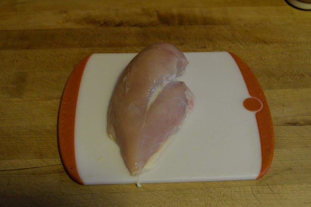 a chicken breast, on a cutting board.