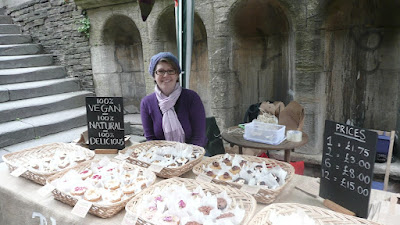 Woman sat at a market stall selling cupcakes, MS