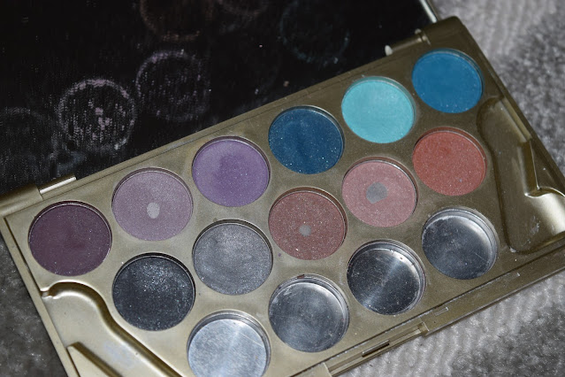An eyeshadow palette with 11 shades in. Three are showing the bottom pan due to use.