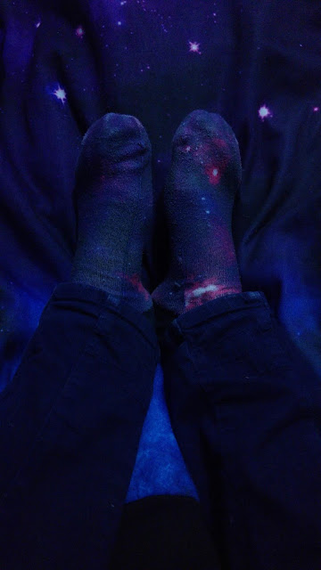 Foto de calcetines con estampado de universo sobre un fondo de galaxia