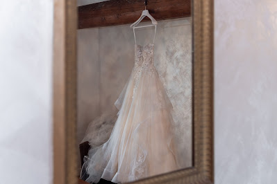 Vestido de novia colgado en una percha reflejándose en un espejo