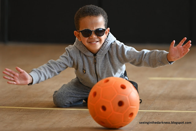 A blind toddler playing with an orange sound ball