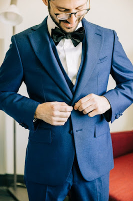 groom buttoning navy blue suit jacket