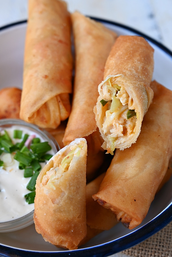 a white plate with quick buffalo chicken egg rolls with ranch dip