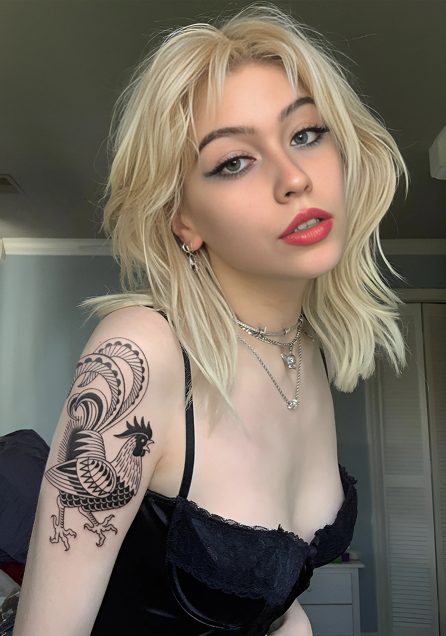 Una modelo con aspecto de borracha, lleva un tatuaje de gallo en el brazo