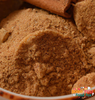 A close-up of a small bowl with a mixture of brown sugar and cinnamon. The mixture is light brown in color and has a fine texture.