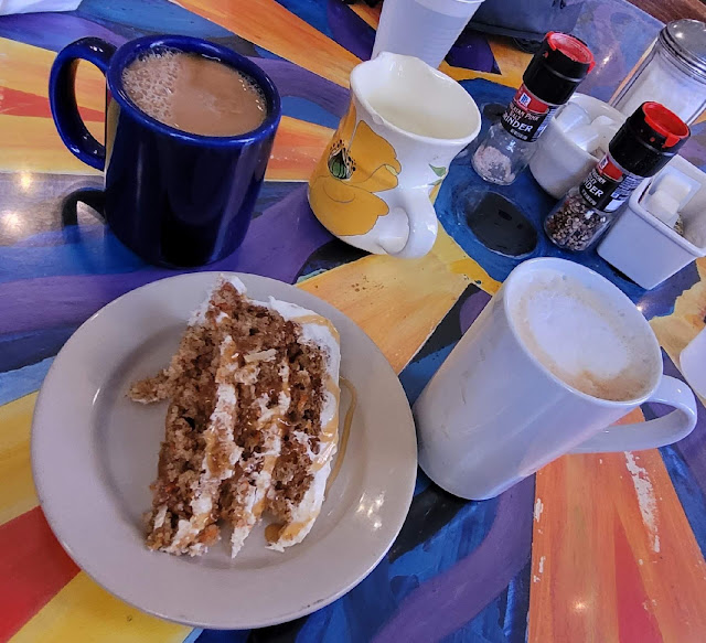 Two cups of coffee and cake on a cafe table.