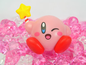 A figure of Nintendo Kirby holding a star-wand, sitting on gems 