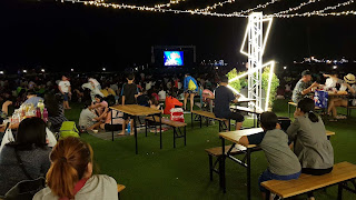 Photograph: Tables and chairs at Sentosa Movie by the beach. People sitting on chairs to watch movie.