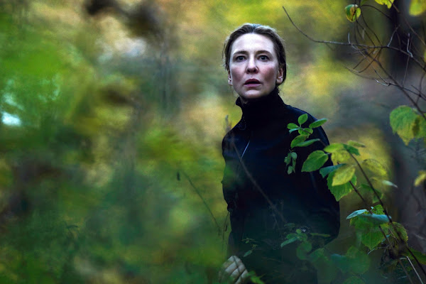 A woman in a black turtleneck walks in the woods