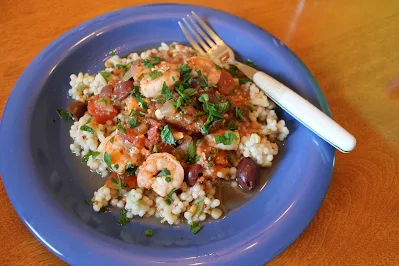 Baked shrimp with tomatoes and feta over couscous on a plate.