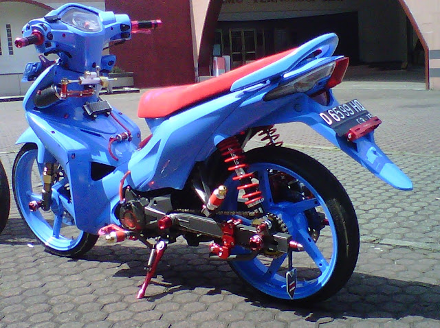 Foto Modifikasi Honda Revo Full warna di bagian seluruh bodi motor dibalut dengan airbrush warna biru muda termasuk juga pada lingkar pelek pun juga diubah warna biru untuk bagian jok tipis berwarna merah yang terlihat garang serta shocbreaker hingga aksen dibagian bawah mesin motor