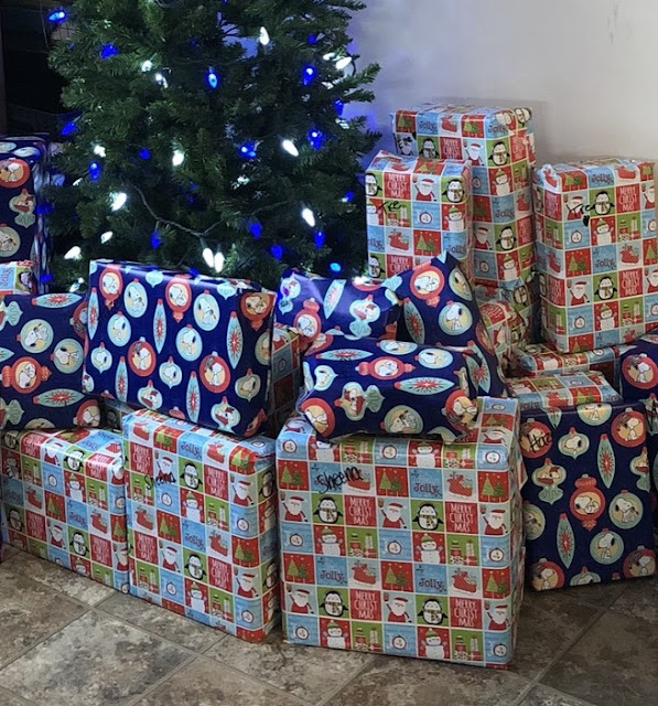 wrapped christmas gifts stacked in front of a tree.