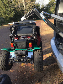 off road powerchair suspended in midair from a hoist coming out of a boot