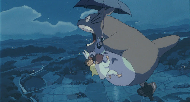 Film still from My Neighbour Totoro. Totoro is taking Mei, Satsuki and the other forest spirits flying over the forest.