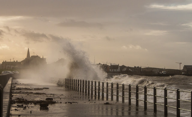 Photo of debris on the Promenade and another wave being blown across the walkway