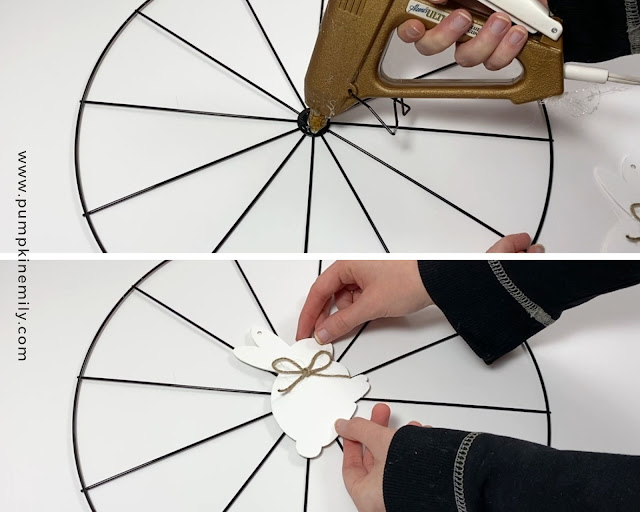 Gluing on a wood bunny ornament to the middle of a bicycle wheel wreath form.