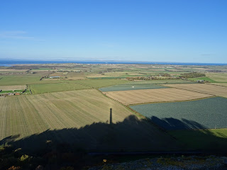 A view over the land from the Hopetoun Monument showing fields stretching off into the distance.  The silhouette of the monument and the hill on which it sits can be seen on the land below.  Photo by Kevin Nosferatu for the Skulferatu Project.