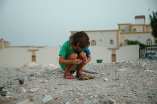 a little girl bent over holding an object in her hands with face down