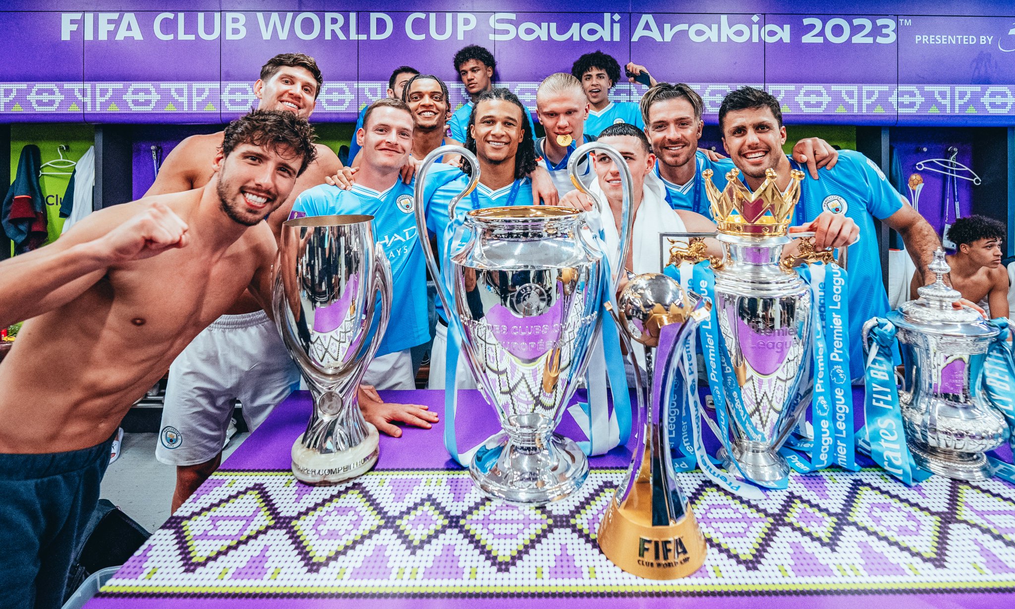 Manchester City players pose with the Club's five (5) trophies won in one (1) year