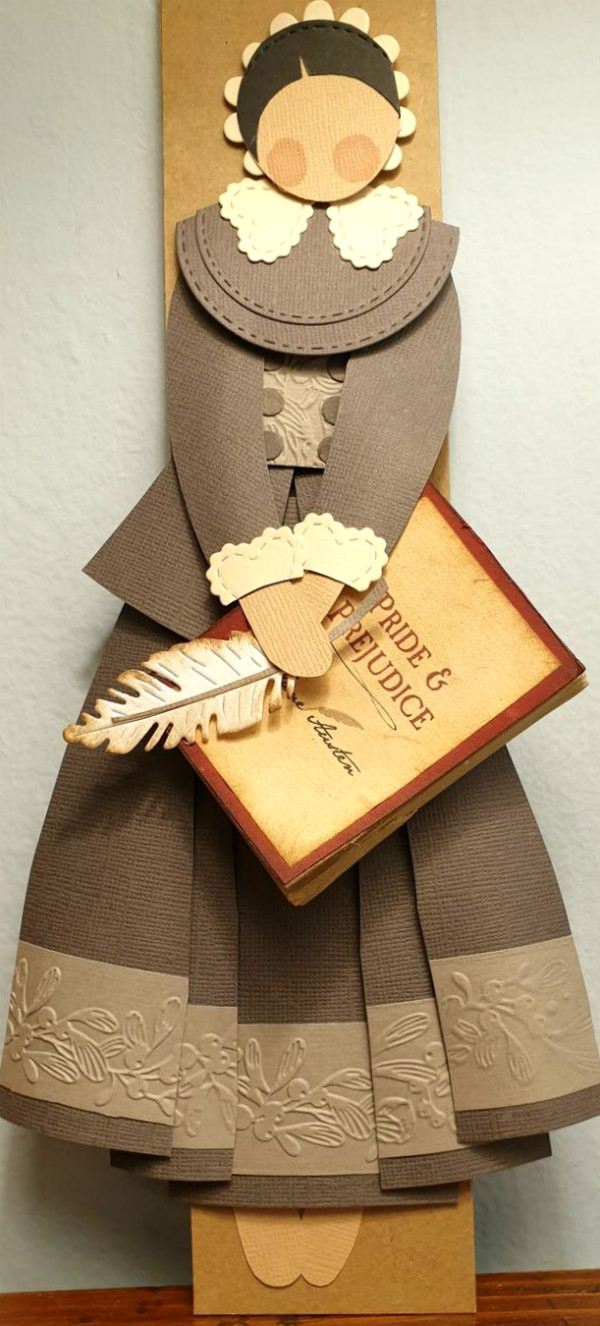 Jane Austen papercut figure holding papercut quill pen and Pride and Prejudice book