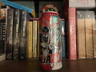 An unopened can of Ninja Vs. Unicorn on a bookshelf.