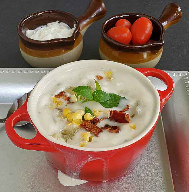 easy corn chowder made with cream corn and fresh corn in a red crock with sour cream and grape tomatoes in small crocks